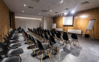 Salle de séminaire vide avec chaises noires, paperboards et écran blanc