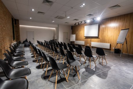 Salle de séminaire vide avec chaises noires, paperboards et écran blanc